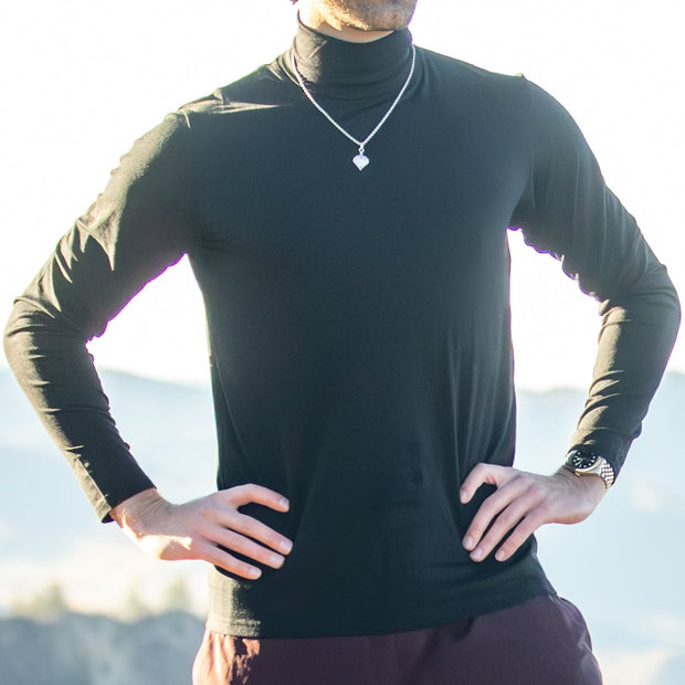 Man wearing a black Merino Turtleneck with a blurred natural background