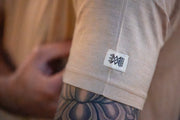 Close-up of a Silk Cashmere Merino T-Shirt with the Aspen Merino logo, showing a tattooed arm.