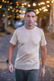 Man wearing a Silk Cashmere Merino T-Shirt and dark pants walking on a street with blurred lights in the background