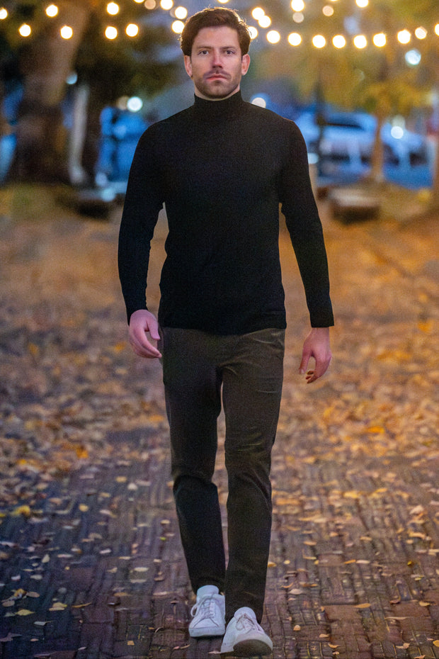 Man walking on a path with string lights above him