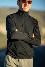 Man wearing a black Merino Turtleneck and sunglasses with a blurred natural background