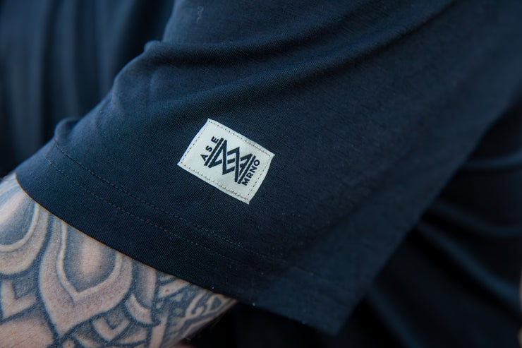 Close-up of a Men's Merino Short Sleeve with the Aspen Merino logo on the sleeve, featuring tattooed arm.